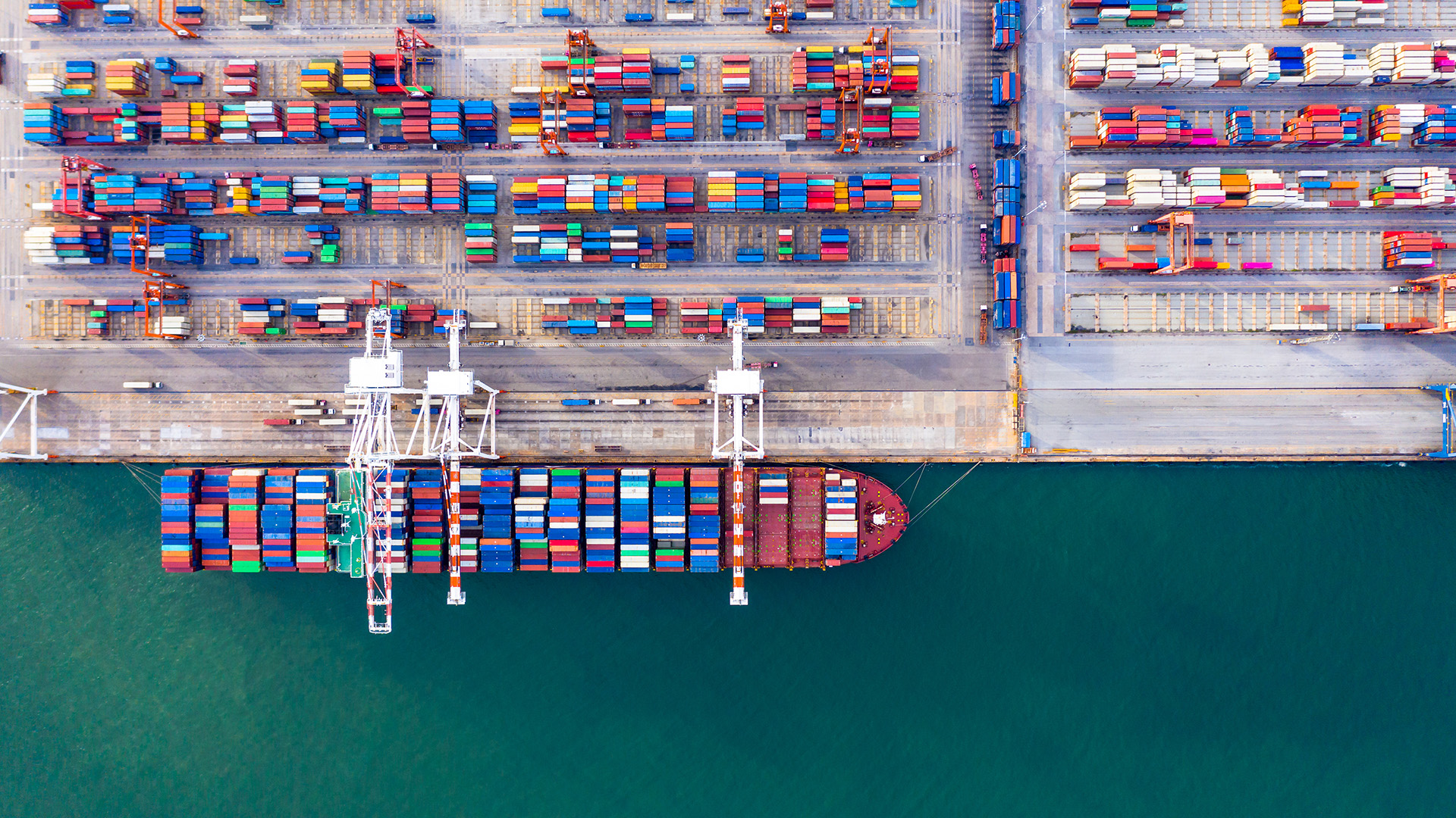 Overhead view of a large ship loading containers from cranes at a major port