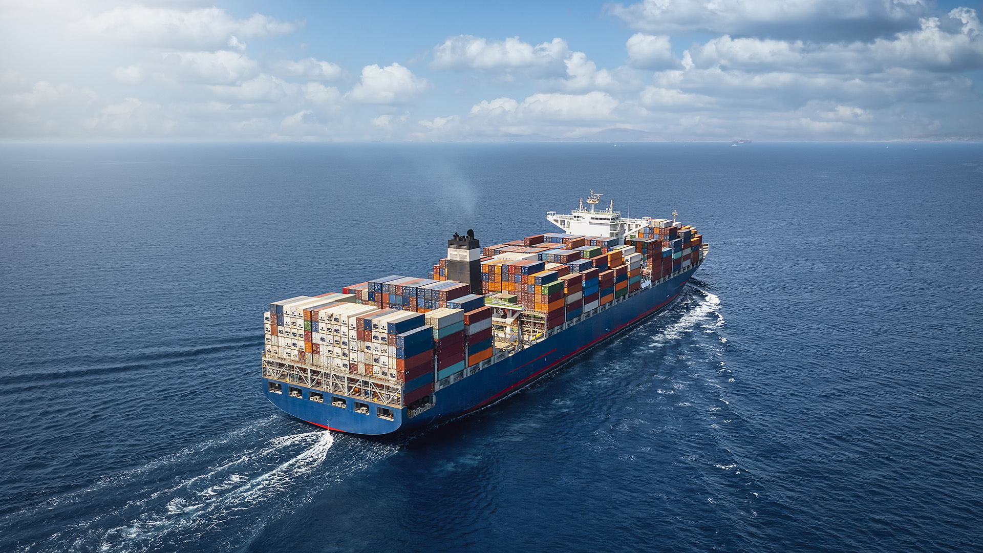 A large container ship crosses steel blue ocean waters