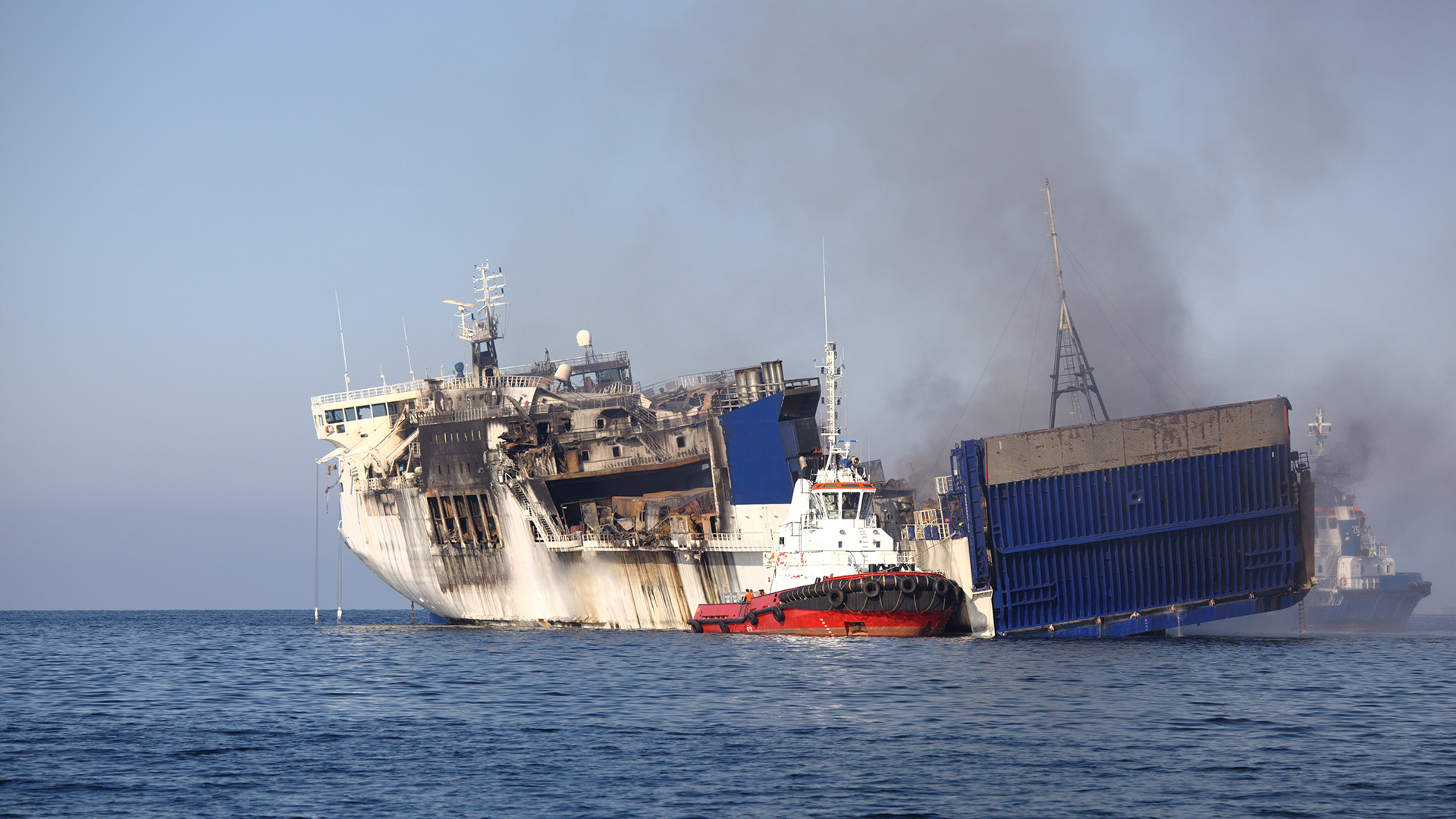 The hull of a white ferry, charred from fire and smoke
