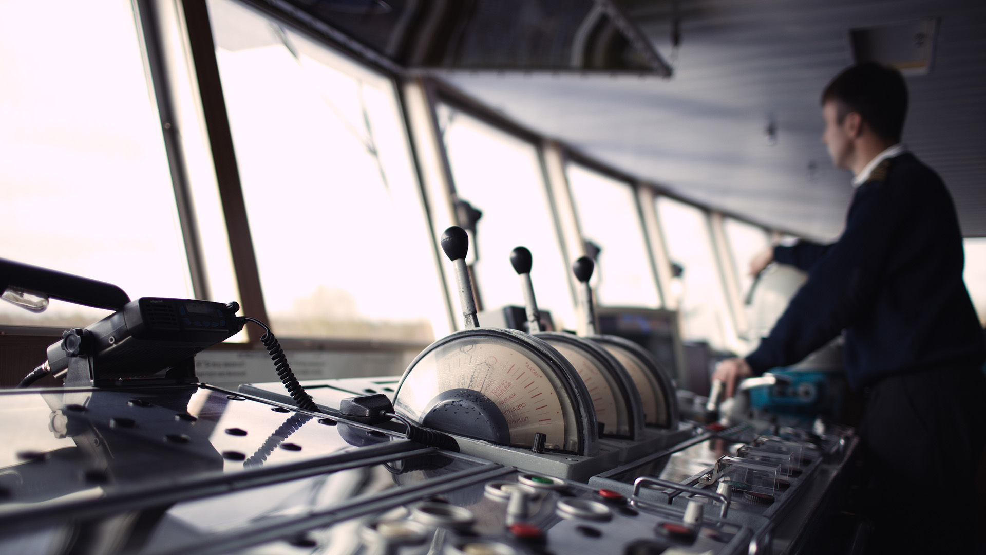 A captain looking out the windows of the bridge on a ship