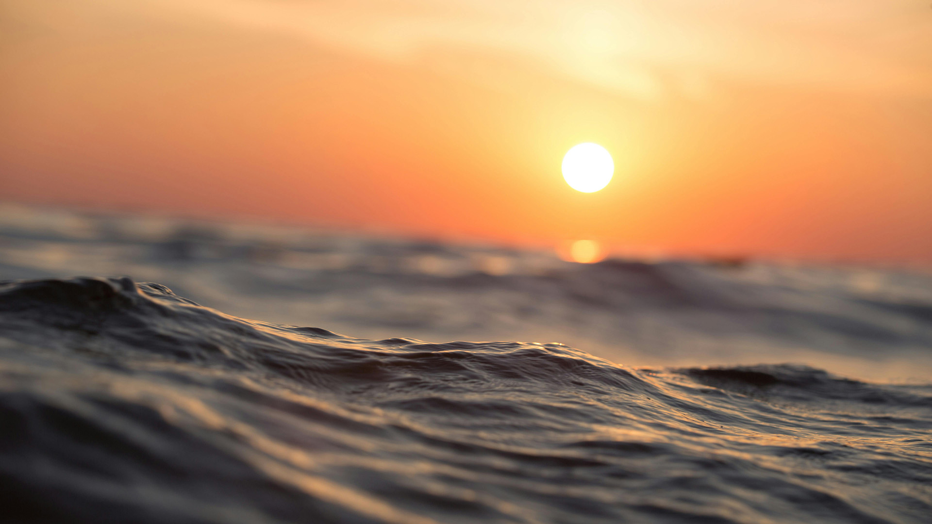 Orange sunset over grey ocean water