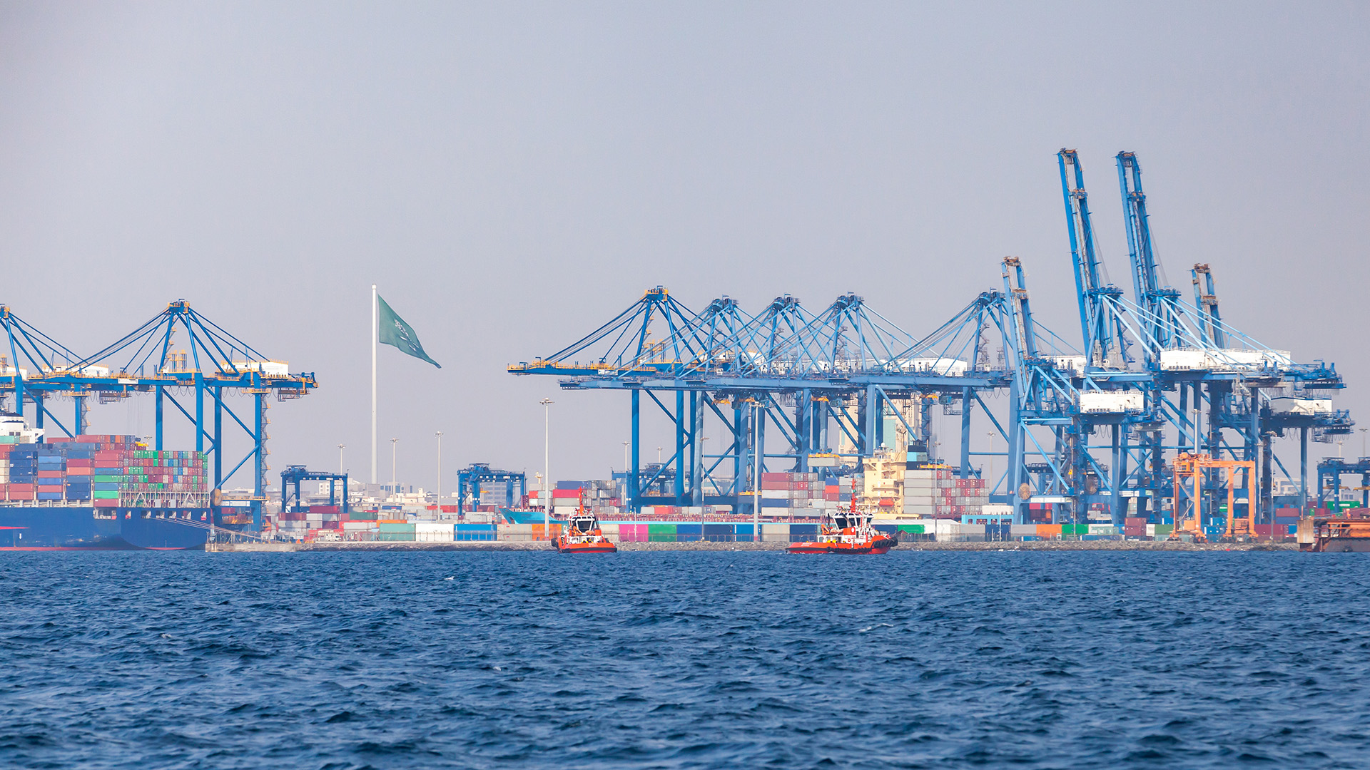 Gantry cranes unload container ships on a sunny summer day. Jeddah port, Saudi Arabia