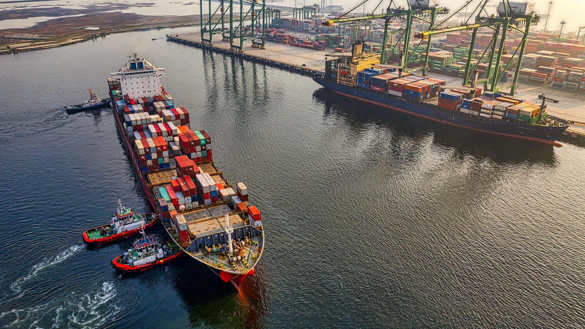 Aerial shot of cargo ship being pushed into port