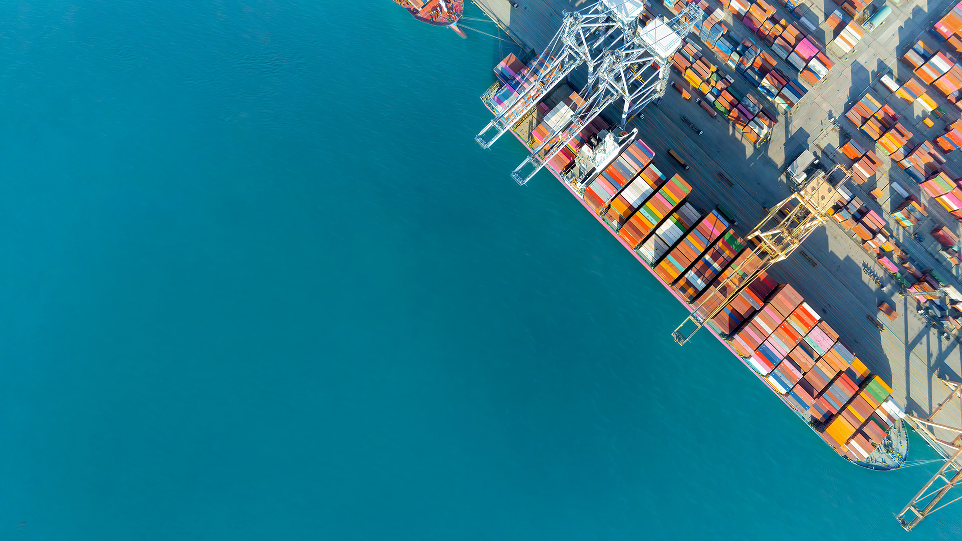 Aerial view of a container ship in port with dock cranes
