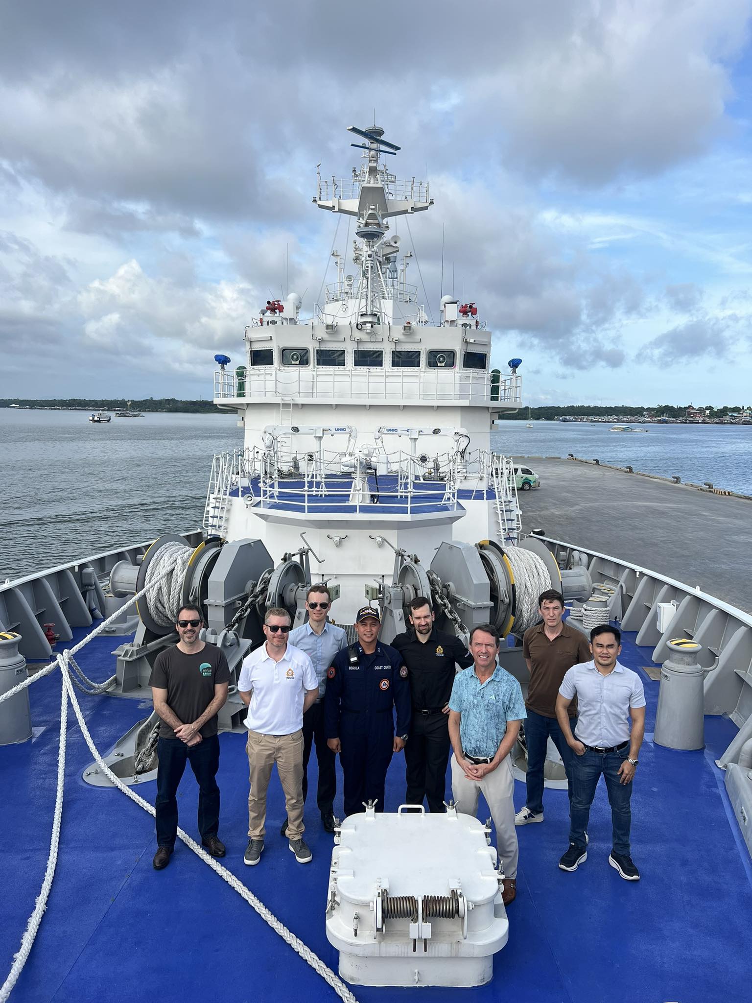 Members of the OceanMind team on the deck of a ship with enforcement teams from Canada and the Philippines