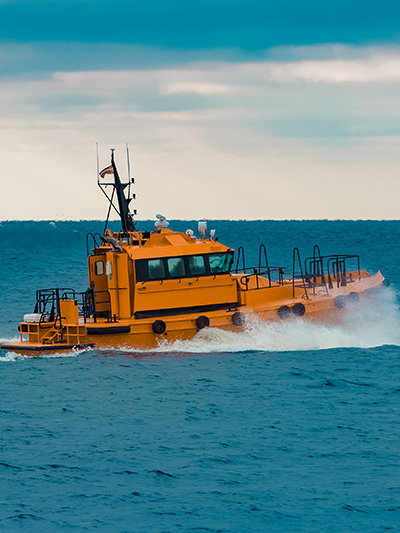 An orange patrol boat races across a teal ocean
